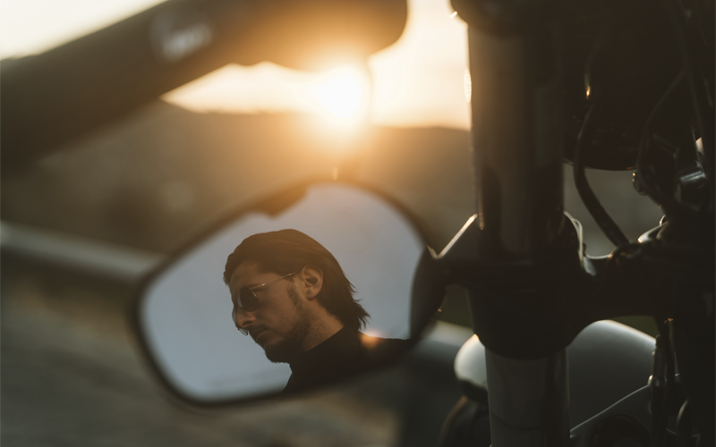 handsome-biker-looking-away-through-mirror